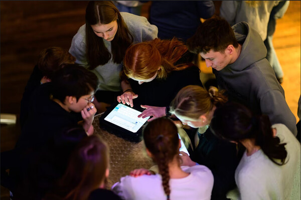 Schüler*innen, die sich über ein Laptop beugen